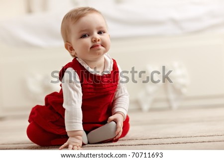 portrait of 6 months female child sitting on floor in red clothes and looking at camera. Horizontal shape, front view, copy space