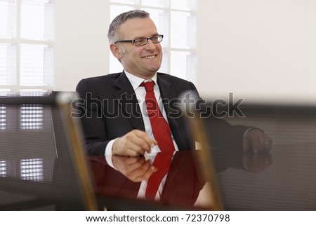 Portrait of caucasian mid adult business man talking to colleagues in meeting room. Horizontal shape, side view, copy space