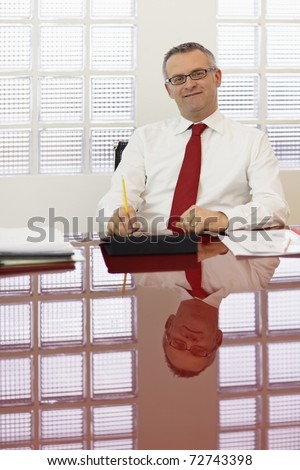 Portrait of caucasian business man leaning on chair with tablet pc, looking at camera. Vertical shape, front view, copy space
