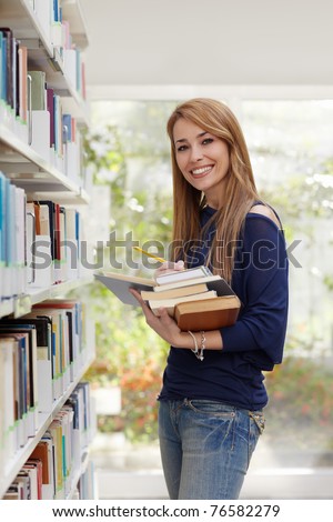 stock photo female blonde college student taking book from shelf in