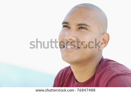 stock photo portrait of young hispanic guy with shaved head looking up to 
