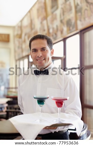 hispanic waiter serving adult couple at table in restaurant and looking at camera. Horizontal shape, front view, waist up