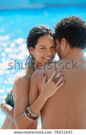 Honeymoon: happy young newlyweds smiling and relaxing near hotel pool. Vertical shape, waist up, copy space