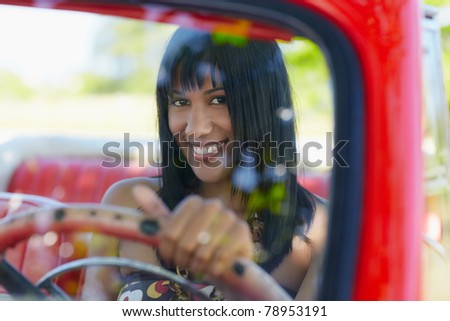 young adult brunette woman driving convertible red car and looking at camera. Horizontal shape, front view