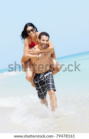 happy maried adult couple having fun and playing on the sea shore in cuba. Vertical shape, full length, copy space