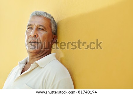 portrait of 50 years old latin american man having problems and leaning on yellow wall. Horizontal shape, copy space