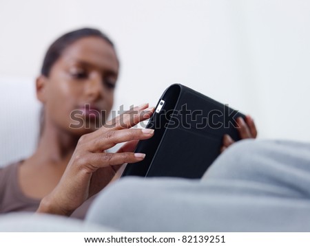 close up of mid adult indian woman relaxing on sofa and using touch pad computer. selective focus, copy space