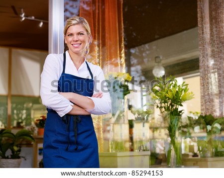 Portrait of beautiful caucasian girl self-employed in flower shop, smiling and looking at camera. Horizontal shape, waist up