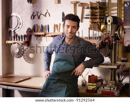 Portrait of adult italian man at work as craftsman in shop with tools in background