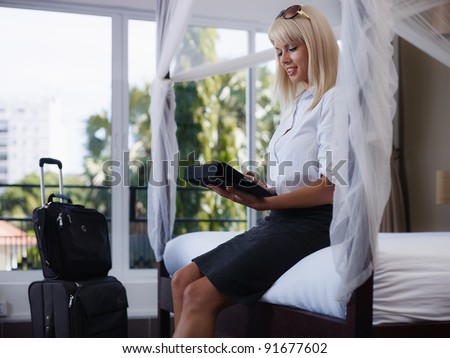 Mid adult caucasian businesswoman typing on tablet pc in hotel room during business travel. Side view, three quarter length