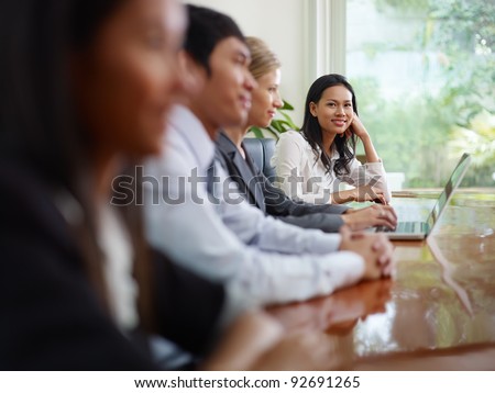 Beautiful young asian woman working and smiling at camera during business meeting with colleagues.