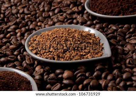Three types of coffee in small cups on coffee beans;