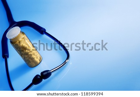 Stethoscope and medicine bottle on blue background