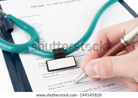 Hand filling in medical questionnaire form in a clipboard isolated on white background