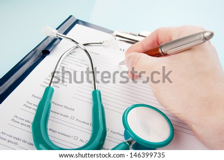 Doctor filling in medical questionnaire form with stethoscope in a clipboard isolated on white background