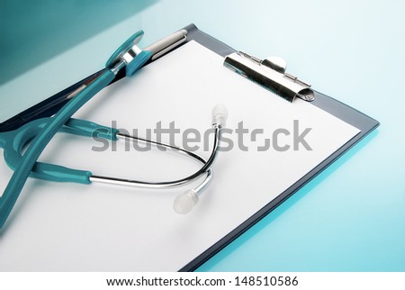 Stethoscope and empty document in a clipboard on blue background