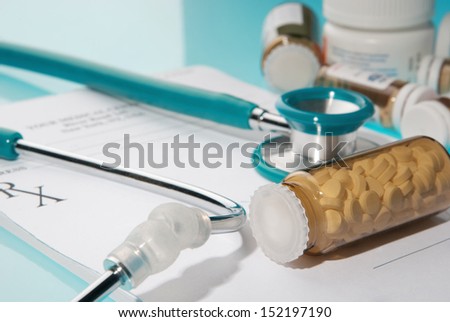 Empty medical prescription with a stethoscope and medicine bottles on blue reflective background