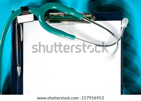 Stethoscope and empty document in a clipboard on Xray photo of lungs