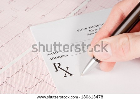 Doctor filling in empty medical prescription on electrocardiogram (ECG) chart