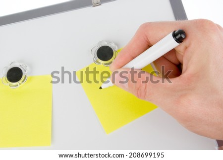 Hand noting down on yellow notes on magnetic board (whiteboard)
