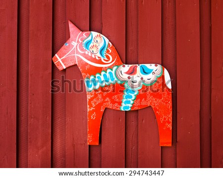 NUSNAS, DALARNA, SWEDEN - JUNE 20, 2015: Dalarhest, traditional wooden horse, tablet on the copper red wooden wall of traditional rural house