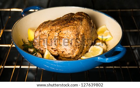 Pork Shoulder Roasting in Oven with Herbs and Lemons