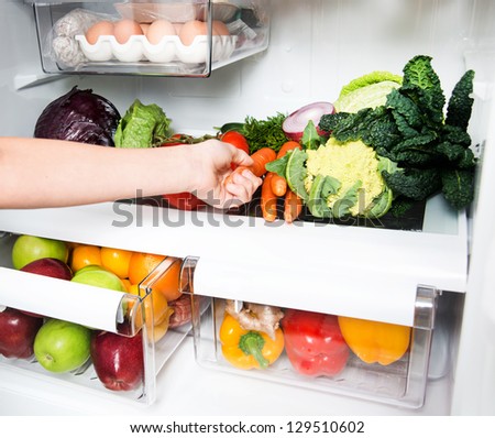 Hand Reaching for Snack in Refrigerator Full of Healthy Food Options