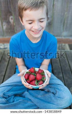 Smiling Boy Holding Bowl of Fresh Strawberries