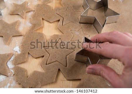 Hand Cutting Out Shapes from Rolled Out Ginger Cookies Dough with Star Cutters