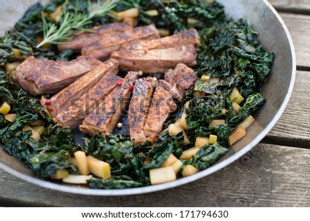 Grass Fed Beef Steak Seared and Sliced Served with Wilted Kale on Stainless Steel Skillet