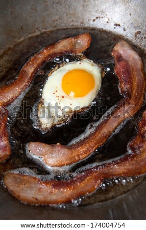 Striped of Bacon and Fresh Egg Fried on Skillet for Simple Traditional Breakfast