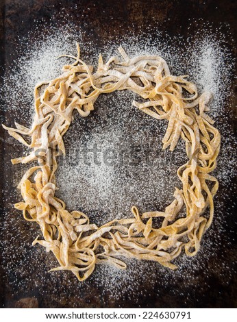 Fresh Pasta Tagliatelle from a Traditional Pasta Machine Forming a Circle on Dark Metal Sheet