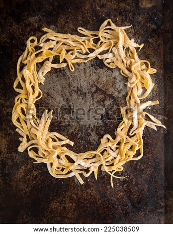 Fresh Pasta Tagliatelle from a Traditional Pasta Machine Forming a Circle on Dark Metal Sheet