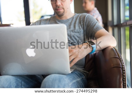 SEATTLE, USA - May 2, 2015: Man Wearing Apple Watch While Working on Computer at Local Coffee Shop