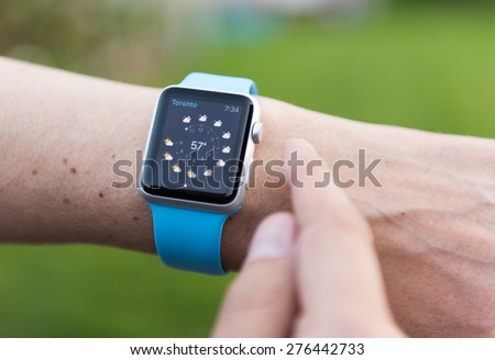 SEATTLE, USA - May 8, 2015: Man Using Weather App on Apple Watch. Showing Toronto Weather Forecast.