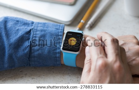 SEATTLE, USA - May 17, 2015: Man Wearing Sport Apple Watch with Blue Rubber Band. Happy Face Emoji with Heart Shaped Eyes Displayed.
