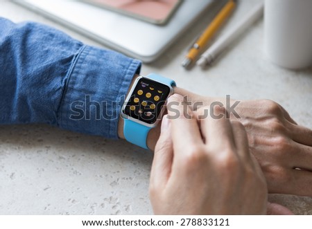 SEATTLE, USA - May 17, 2015: Man Wearing Sport Apple Watch with Blue Rubber Band. Emoji Collection Displayed.