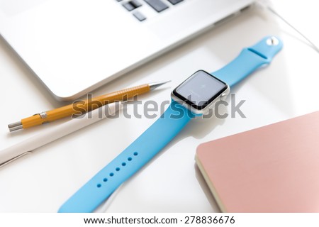SEATTLE, USA - May 17, 2015: Sport Apple Watch with Blue Rubber Band Charging While Connected to MacBook Pro.