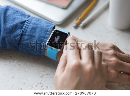SEATTLE, USA - May 17, 2015: Man Wearing Sport Apple Watch with Blue Rubber Band. Hand Gesture Emoji Displayed.