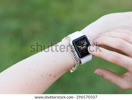 SEATTLE, USA - July 15, 2015: Woman Using Apple Watch While Outside. Checking Time with App.