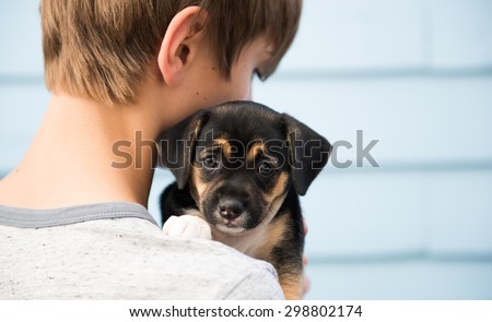 Young Boy Holding Black and Brown Puppy with Floppy Ears