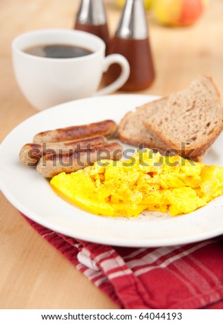 Simple and Delicious Breakfast of Mini Bratwurst Sausages, Eggs Scrambled with Cheese, Toast, and Black Coffee