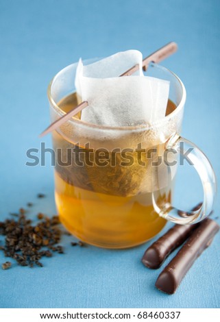 Clear Glass Cup of Loose Green Tea in Paper Filter Bag with Some Chocolate Sticks