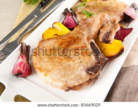 Closeup of Two Pork Chops Served with Roasted Root Vegetables
