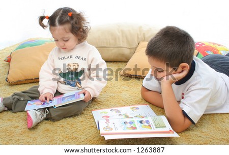 Brother and sister reading books over a carpet. They look interested and concentrated. Visit my gallery for more images of children