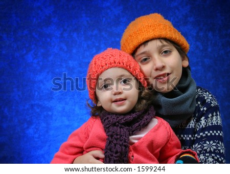 Brother and sister hugging in winter outfit.