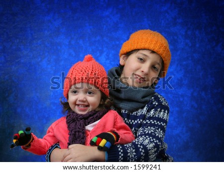 Brother and sister having fun with the snow in winter outfit.