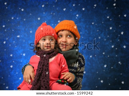 Brother and sister having fun with the snow in winter outfit.