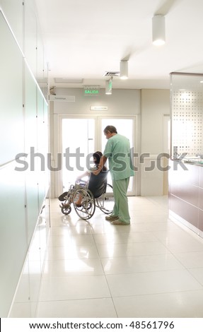 Nurse and a patient using a wheelchair at a hospital hall