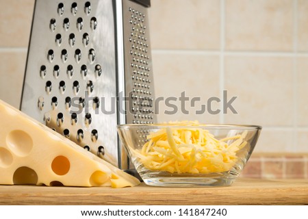 Grated cheese in Glass Bowl with Grater. Front view